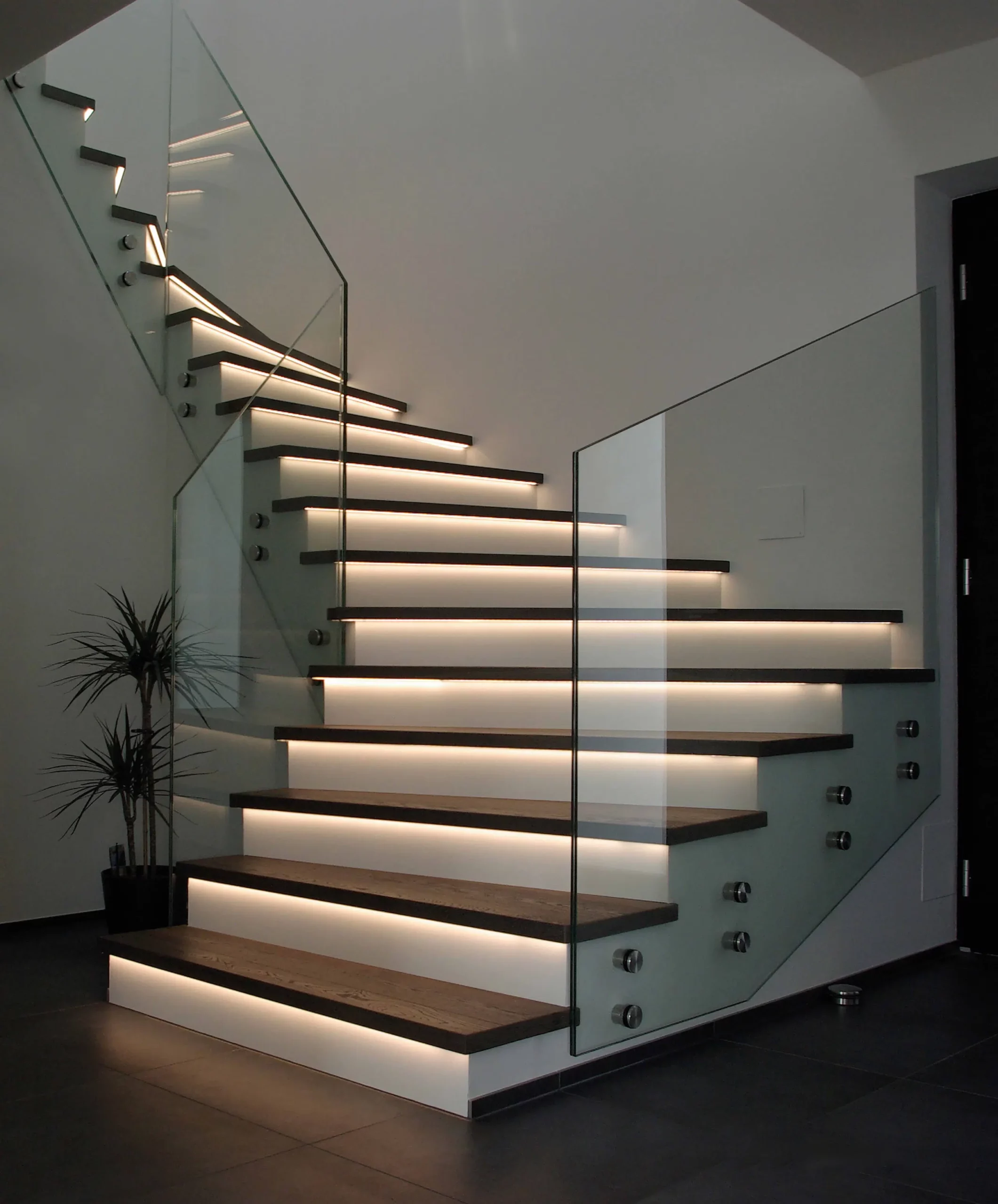 Eine moderne Treppe mit Glasgeländer und LED Beleuchtung an den Treppen - Stufen. Boden Pelzer -Bodenbeläge, Vinylbelag, Parkett - Moselstr. 14 - 41464 Neuss